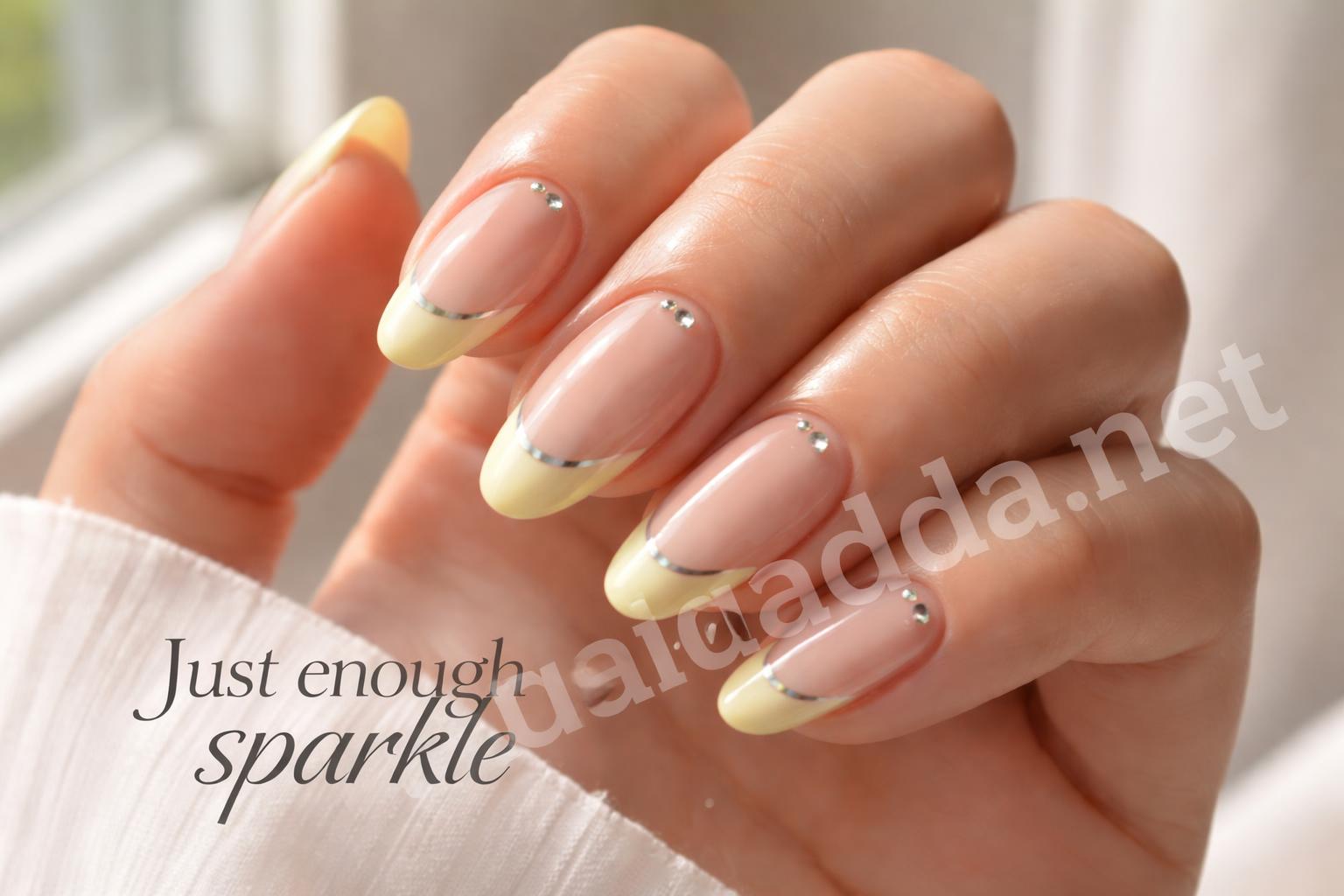 Pastel yellow french tip nails with chrome and rhinestones